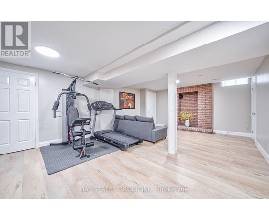 A spacious living room with a grey sofa and a gym setup.