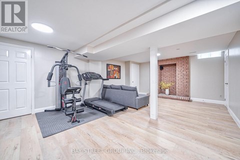 A spacious living room with a grey sofa and a gym setup.