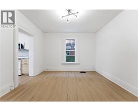 A room with wooden floors and a window showing a city view.