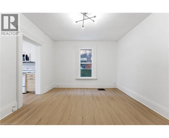 A room with wooden floors and a window showing a city view.