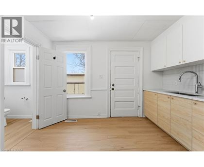 A white room with wooden floors and a sink.