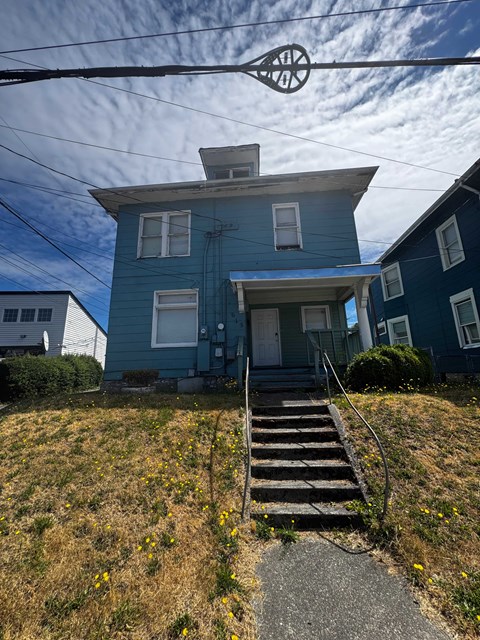 A blue house with a white door and a small porch.