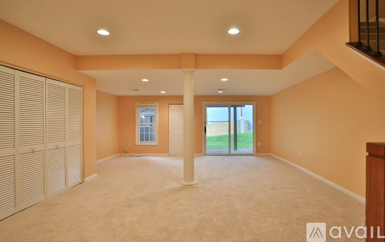 A spacious room with beige carpeting and a large window with a view of the outdoors.