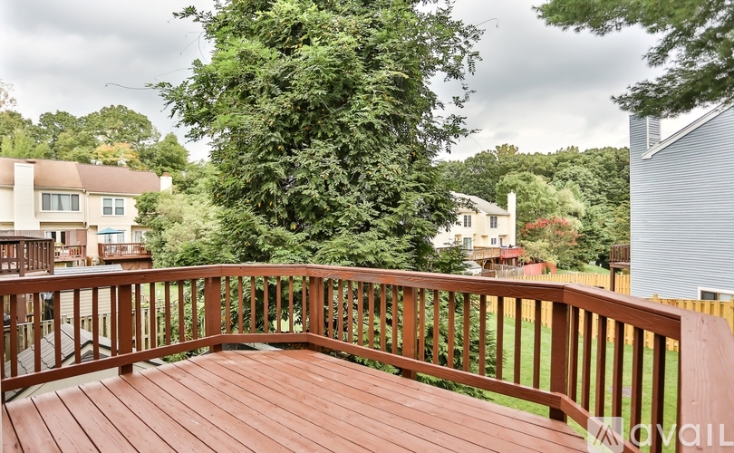 A wooden deck with a railing and a view of a residential area.