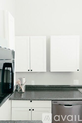 A kitchen with white cabinets and a black microwave.