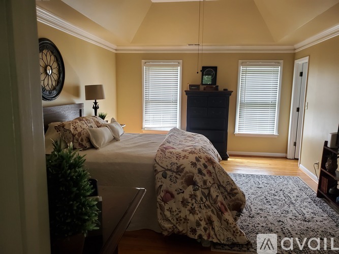 A bedroom with a bed, dresser, and window with blinds.