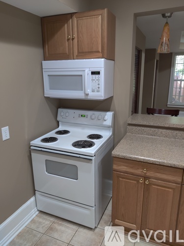 A white microwave oven is mounted above a white stove in a kitchen.