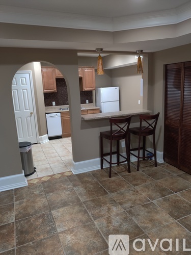 A kitchen with a white refrigerator and brown bar stools.
