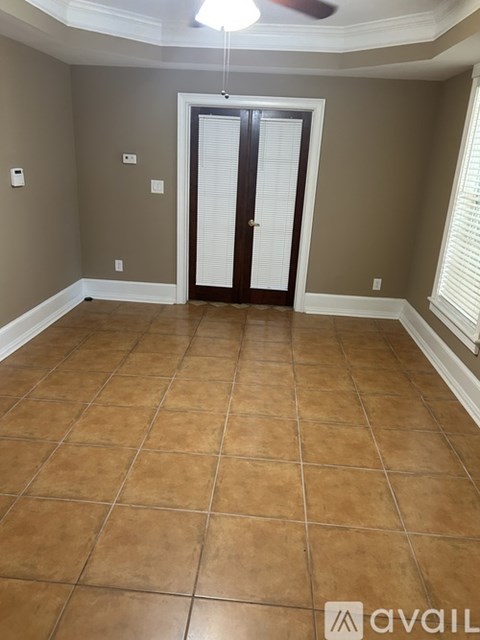 A room with tan tile flooring and a ceiling fan.
