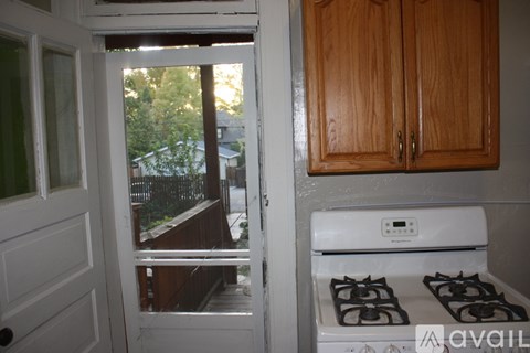 A kitchen with a stove and a doorway leading to a backyard.