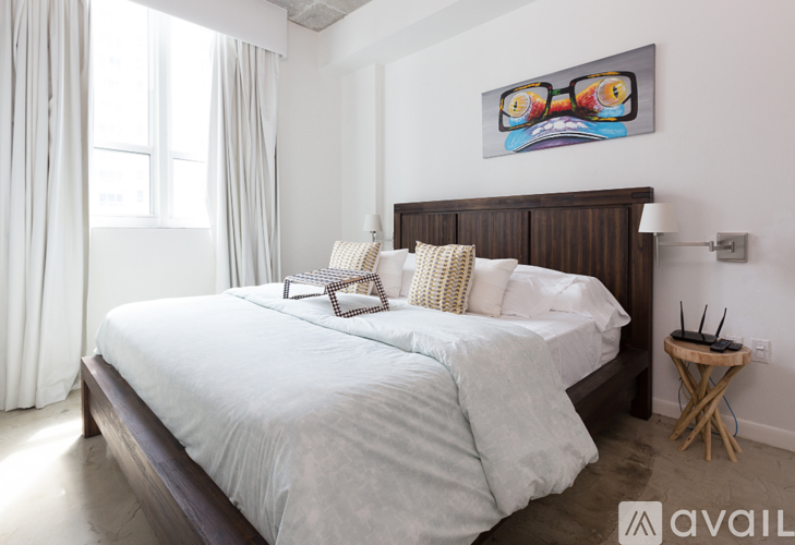 A bedroom with a large bed and a painting on the wall.