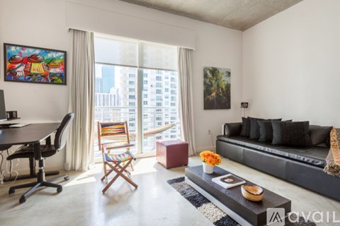 A living room with a black couch, a wooden chair, a coffee table, and a painting on the wall.