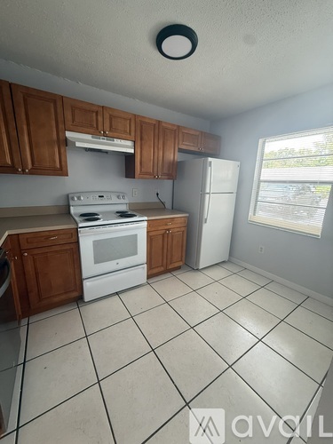 A kitchen with white appliances and brown cabinets.