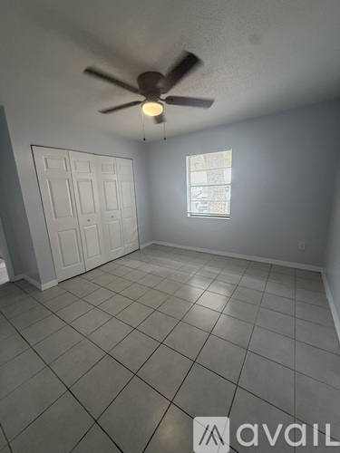 A room with a ceiling fan and a window with a view of a building outside.