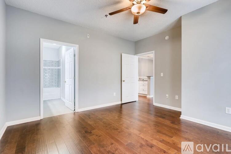 A spacious room with wooden floors and a ceiling fan.