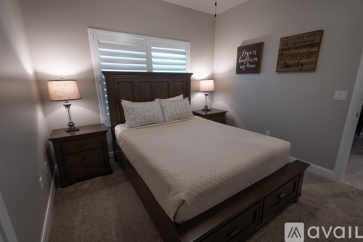 A bedroom with a bed, two lamps, and a wooden headboard.