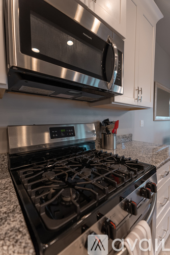 A modern kitchen with a stainless steel gas stove and a microwave above it.
