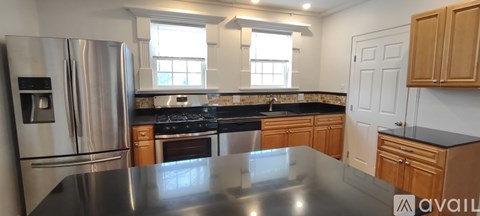 A kitchen with a stainless steel refrigerator and wooden cabinets.