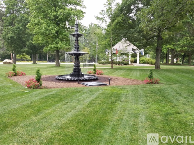 A black fountain in the middle of a grassy park.