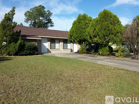 A house with a brown roof and a white garage door is surrounded by trees.