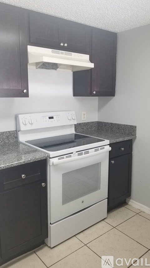 A white stove top oven with a glass door is in a kitchen with dark brown cabinets.