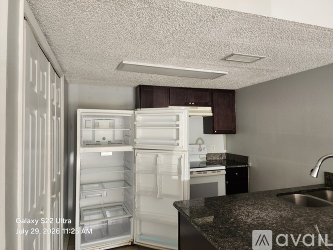 A kitchen with an open refrigerator and a sink.
