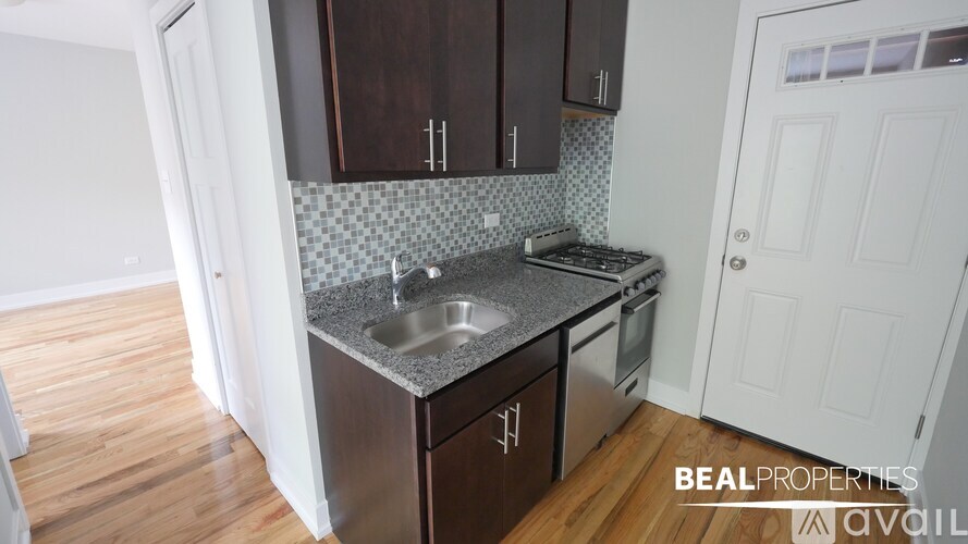 A kitchen with dark brown cabinets and a granite countertop.
