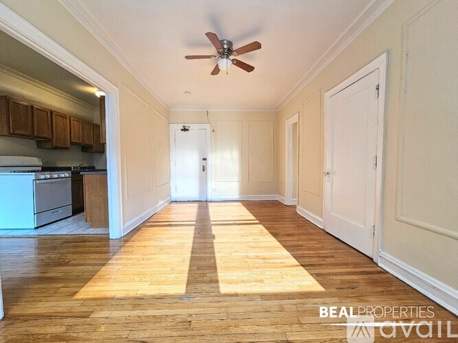 A spacious room with wooden floors and a ceiling fan.