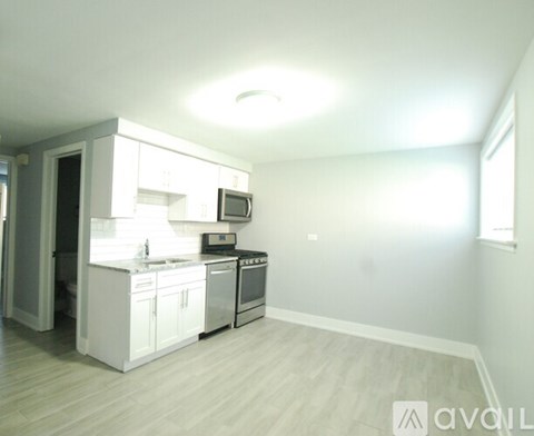 A kitchen with white cabinets and appliances in a room with a window.