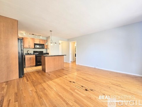 A kitchen with wooden floors and a black fridge.