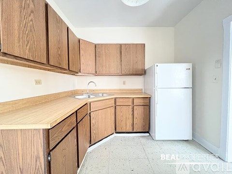 A kitchen with wooden cabinets and a white fridge.