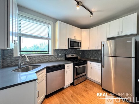A kitchen with a stainless steel refrigerator, sink, and microwave.