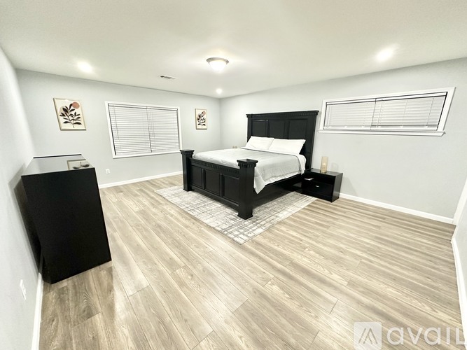 A bedroom with a black bed and wooden flooring.
