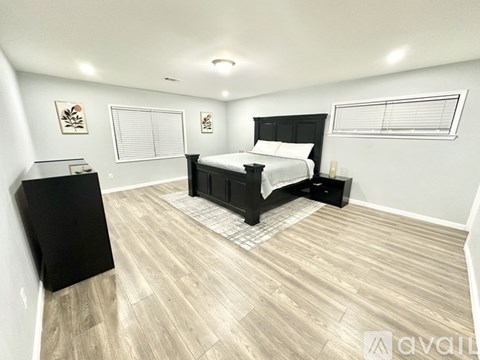 A bedroom with a black bed and wooden flooring.