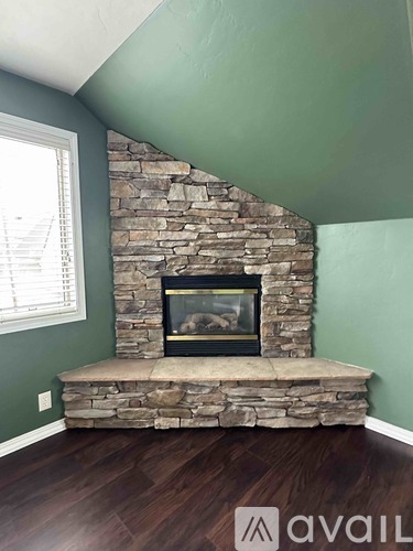 A stone fireplace with a fire going in it.
