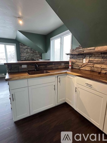 A kitchen with white cabinets and a stone backsplash.