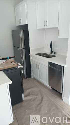 A kitchen with white cabinets and a black fridge.