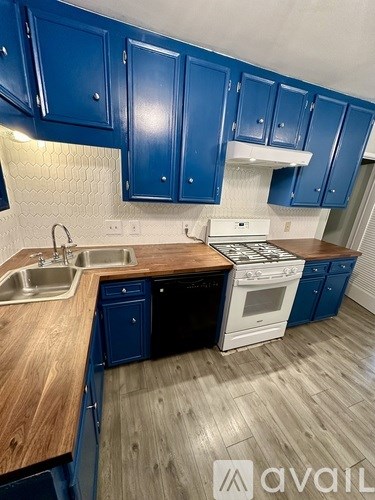 A kitchen with blue cabinets and a white stove top oven.