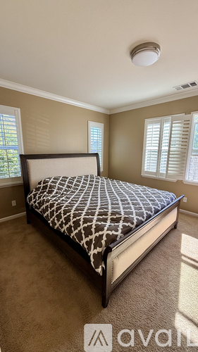 A bedroom with a bed, carpet, and a window.