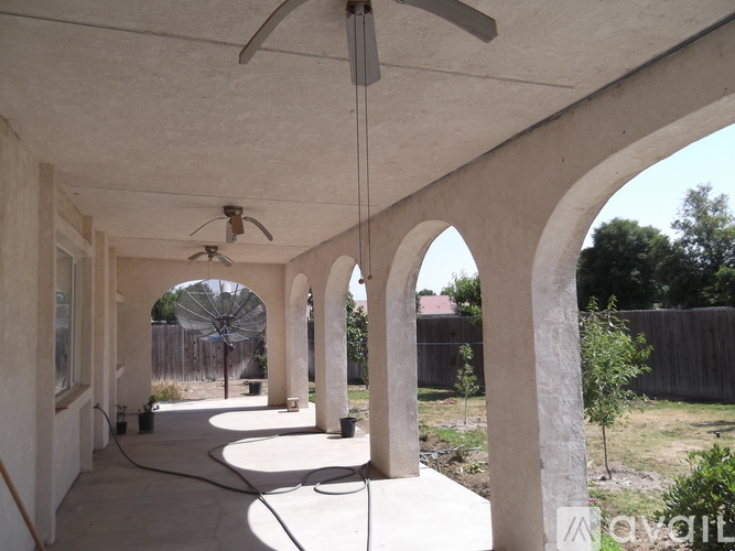 A patio with a fan and arches.
