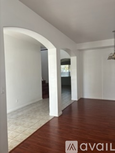 A spacious room with a wooden floor and white walls.