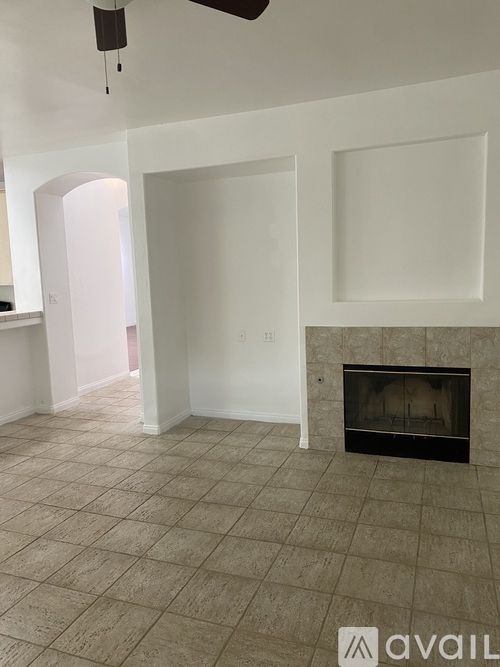 A living room with a fireplace and a fan on the ceiling.