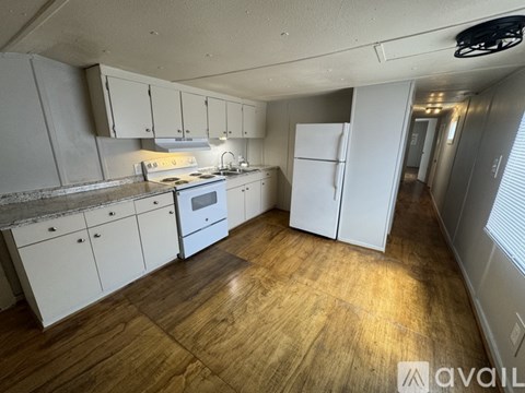 A kitchen with white cabinets and a wooden floor.