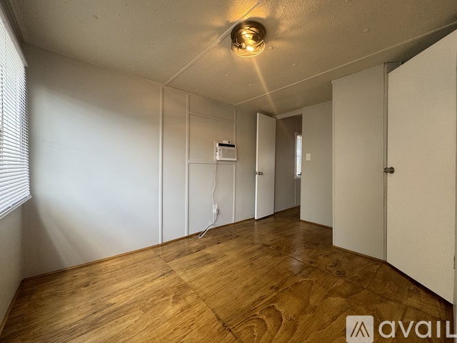 A room with wooden flooring and white walls.