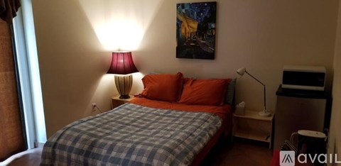 A bedroom with a bed, a nightstand, and a lamp.