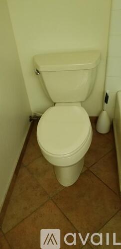 A white toilet in a bathroom with brown tiles.