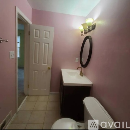 A bathroom with pink walls has a white toilet and sink.