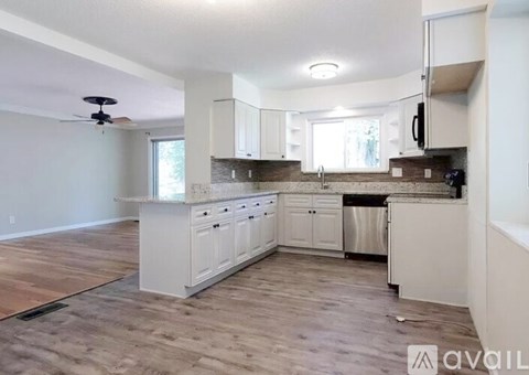 A kitchen with white cabinets and a wooden floor.