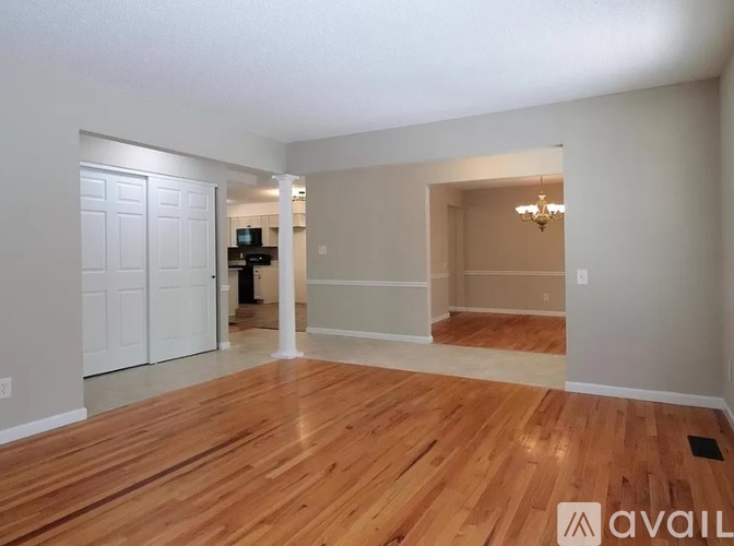 A spacious room with wooden flooring and a chandelier.