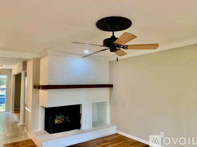 A living room with a fireplace and a ceiling fan.